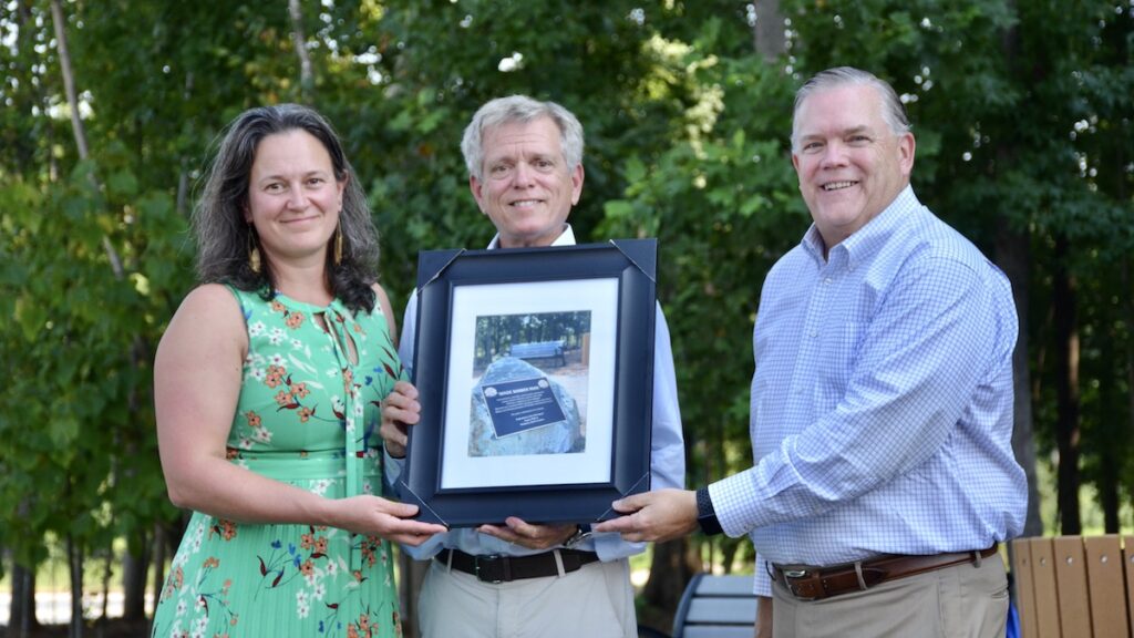 Family members and Kirk Bradley holding a picture of the the plaque for Wade Barber Park. 
