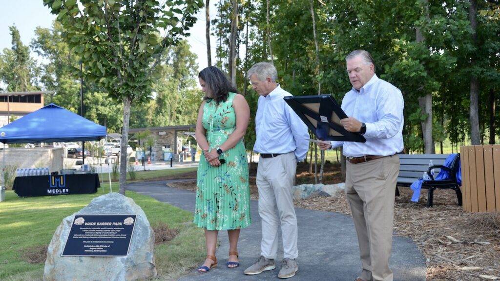 Fmaily members looking at the plaque to dedicate to Wade Barber Park.